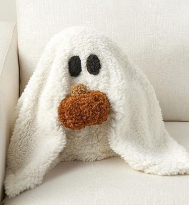 White plush ghost pillow holding a small pumpkin
